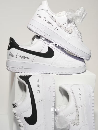 White custom wedding sneakers with pearl and rhinestone embellished swoosh, satin ribbon laces, and personalized last name printed on the side, shown in a close-up detail view