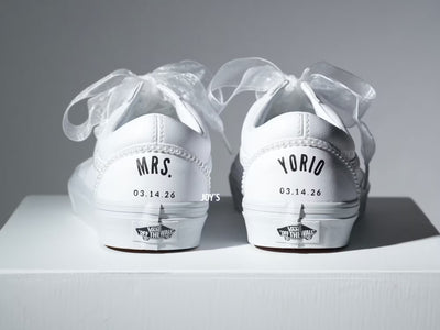 Custom white Vans sneakers with pearl trim and “Mrs.” lettering on the heel, designed as bridal shoes.