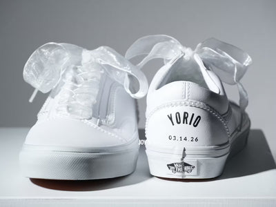 Custom white Vans sneakers with pearl trim and “Mrs.” lettering on the heel, designed as bridal shoes.