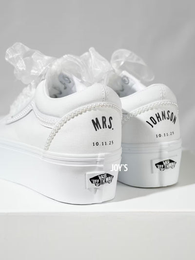 White platform Vans wedding sneakers with pearl trim, satin ribbon laces, and personalized “Mrs.” and last name with wedding date printed on the heels, shown in a rear view