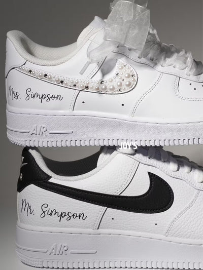 White custom wedding sneakers with pearl and rhinestone embellished swoosh, satin ribbon laces, and personalized last name printed on the side, shown in a close-up detail view