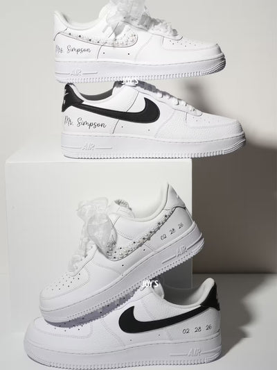 White custom wedding sneakers with pearl and rhinestone embellished swoosh, satin ribbon laces, and personalized last name printed on the side, shown in a close-up detail view