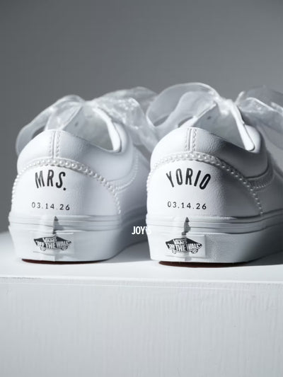 Custom white Vans sneakers with pearl trim and “Mrs.” lettering on the heel, designed as bridal shoes.