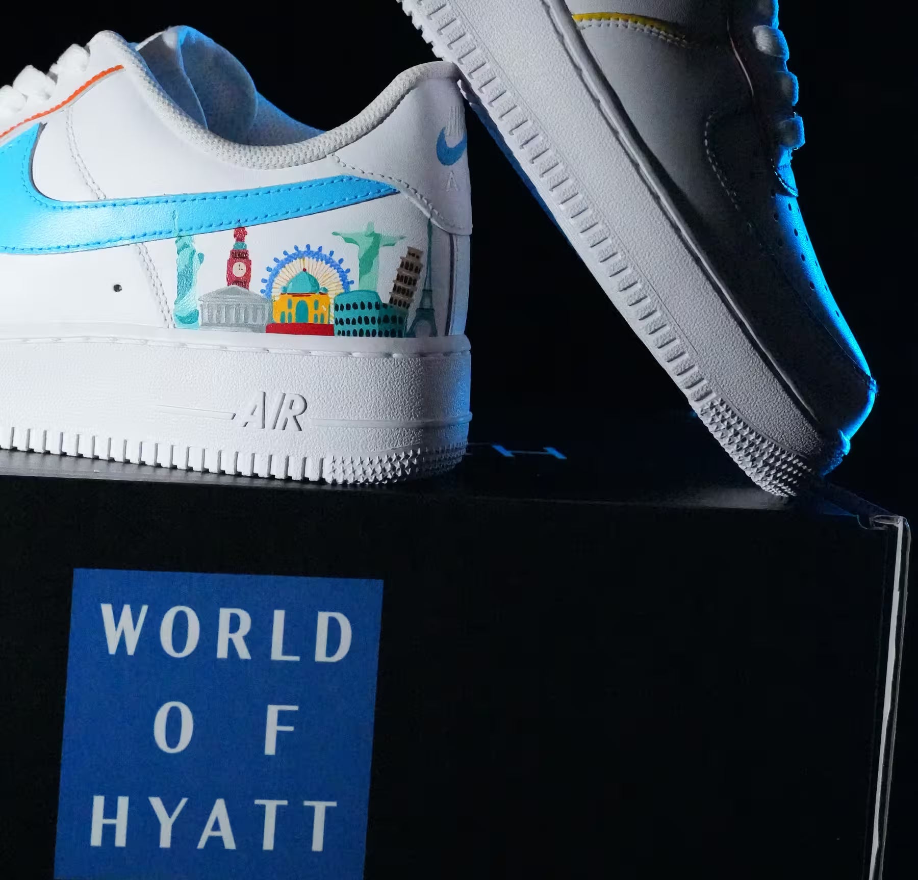 White sneakers with colorful designs on a black platform, featuring 'World of Hyatt' branding.