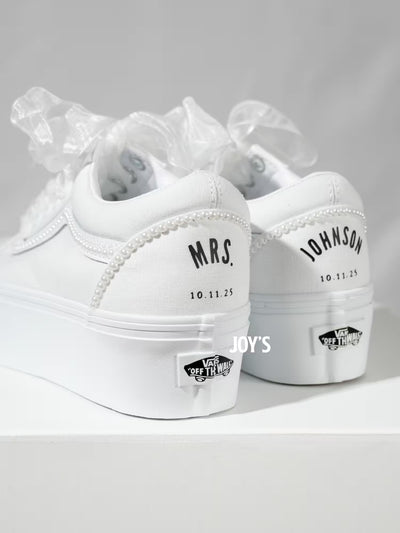 White platform Vans wedding sneakers with pearl trim, satin ribbon laces, and personalized “Mrs.” and last name with wedding date printed on the heels, shown in a rear view
