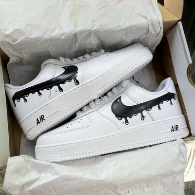 White Nike Air Force 1 with black dripping swoosh detail, shown from the side.